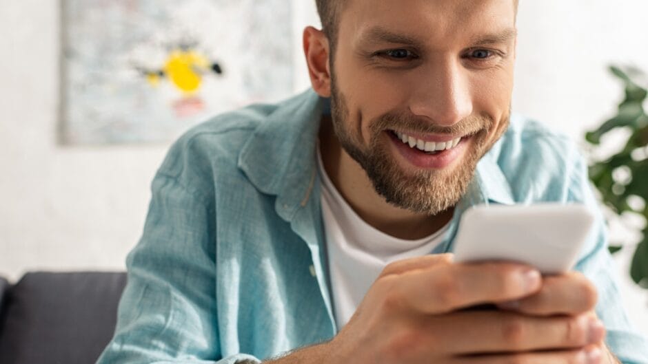 Ein Mann liest auf einem Smartphone und ist offenbar amüsiert
